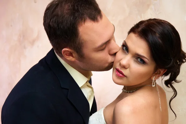 Bräutigam küsst Braut im leeren Zimmer — Stockfoto