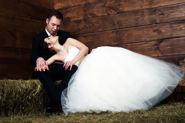 Bride lying on groom's lap in barn — Stock Photo, Image