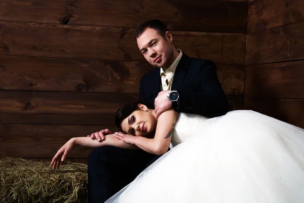 Bride lying on groom's lap in barn — Stock Photo, Image