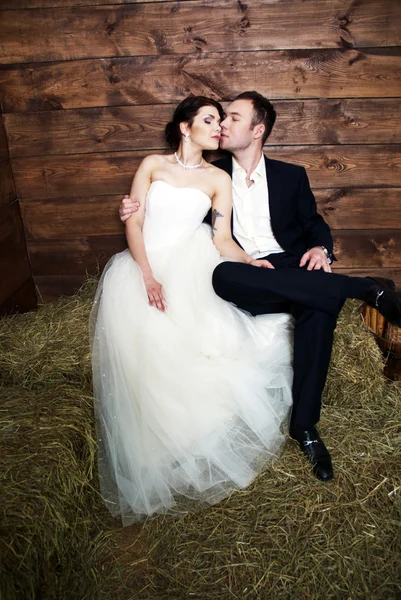 Coppia nei loro abiti da sposa in fienile con fieno — Foto Stock