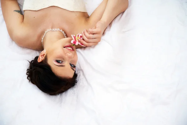 Bride lying in bedroom with orchids — Stock Photo, Image