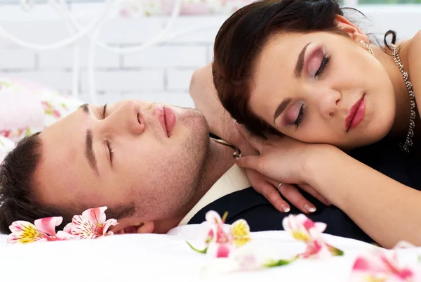 Bruid en bruidegom liggen in slaapkamer met orchideeën — Stockfoto