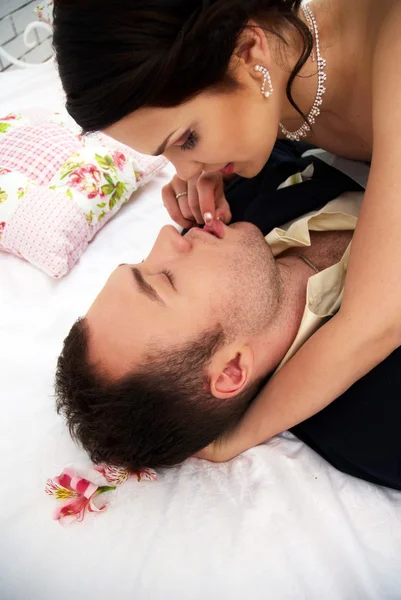 Bruid en bruidegom gek in slaapkamer met orchideeën — Stockfoto
