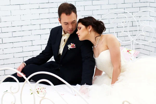 Νύφη και γαμπρός κάθεται στο κρεβάτι στην κρεβατοκάμαρα — Φωτογραφία Αρχείου