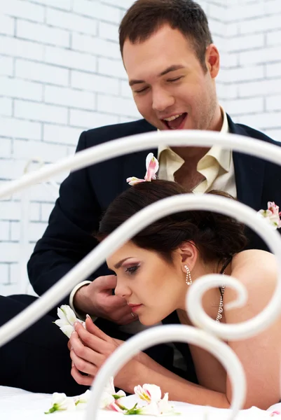 Bride and groom fooling in bedroom with orchids — Stock Photo, Image