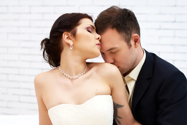 Bruidegom kussen bruid in witte kamer — Stockfoto