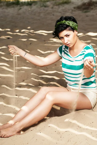 Chica con tatuaje en la playa vierte arena — Foto de Stock