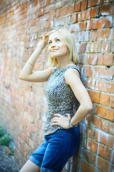Sexy blonde Dame, die in der Nähe einer Mauer steht — Stockfoto