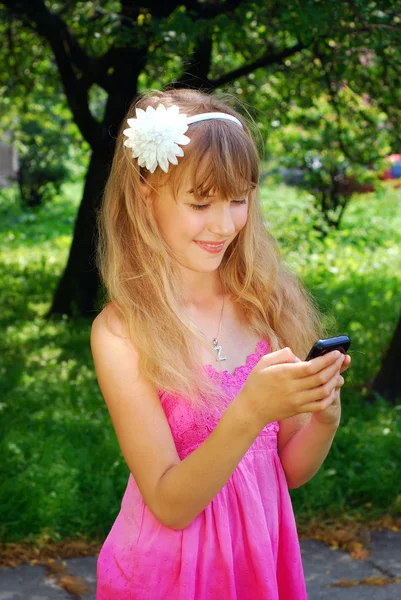 Ung jente med mobiltelefon i park – stockfoto