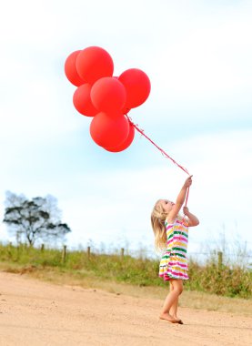 Happy girl plays with her balloons clipart