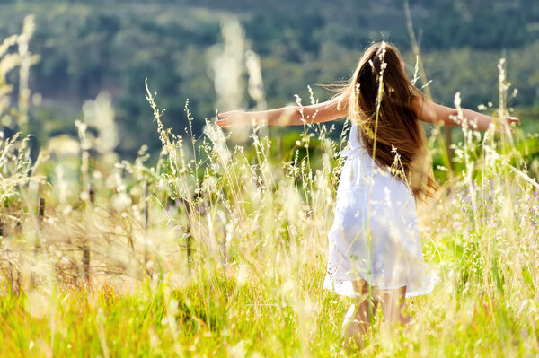 Beautiful girl laughs and dances outdoors in a meadow durning sunset
