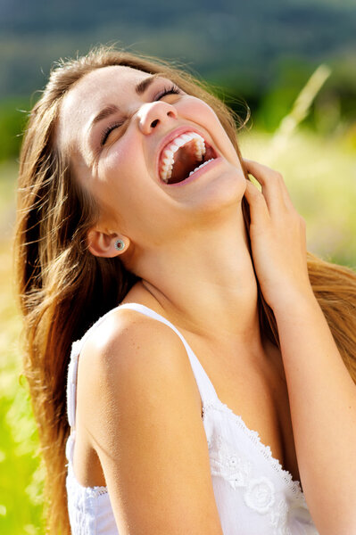 Cute girl laughs with joy outdoors in the sunlight