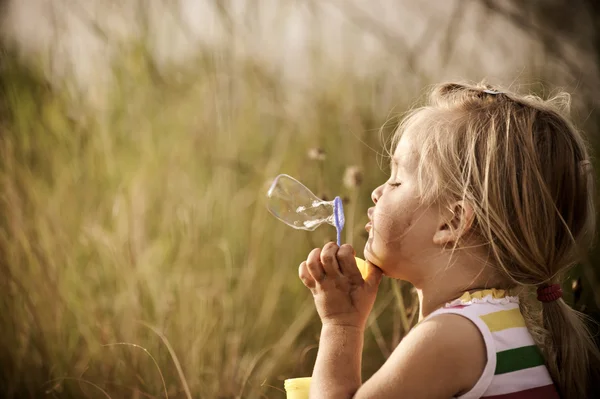 Happy girl blowing bubbles outdoors — Stock Photo, Image