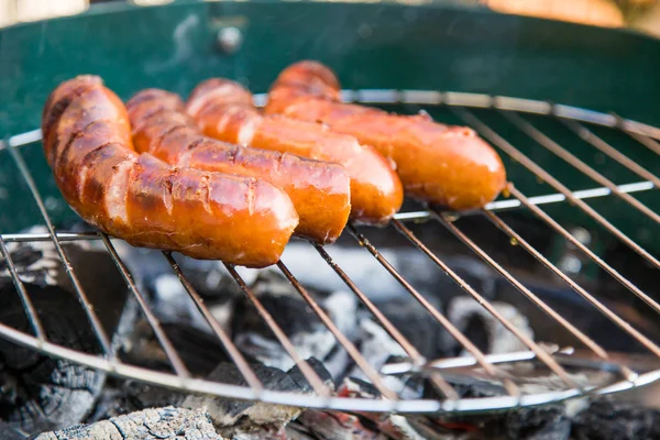 Saucisses savoureuses brûlant sur barbecue chaud — Photo