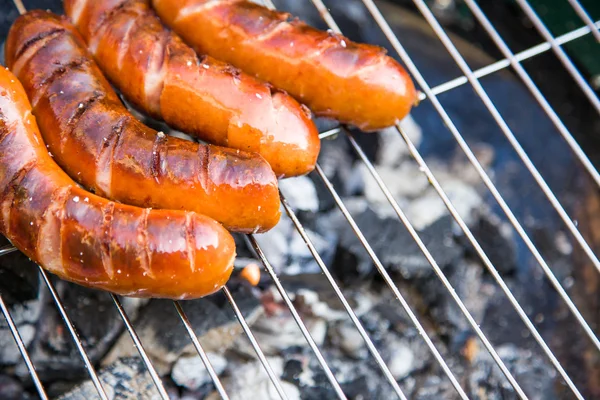 Saucisses savoureuses brûlant sur barbecue chaud — Photo