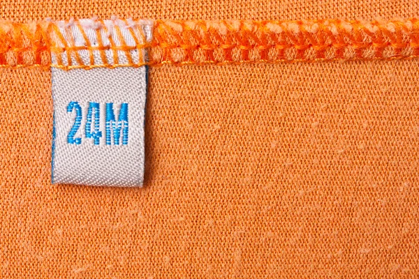 Etykieta na pomarańczowym tkaniny — Zdjęcie stockowe
