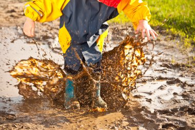 Child splashing in muddy puddle clipart