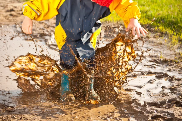 泥だらけの水たまりの中で水しぶき子供 — ストック写真