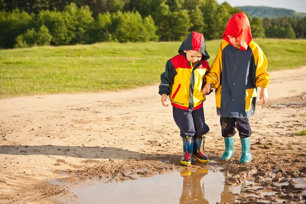 Två pojkar gå genom en lera pöl — Stockfoto