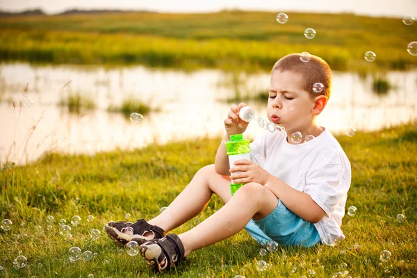 Мальчик пускает пузыри в парке — стоковое фото