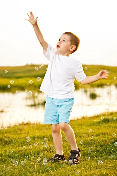 Мальчик ловит пузыри — стоковое фото