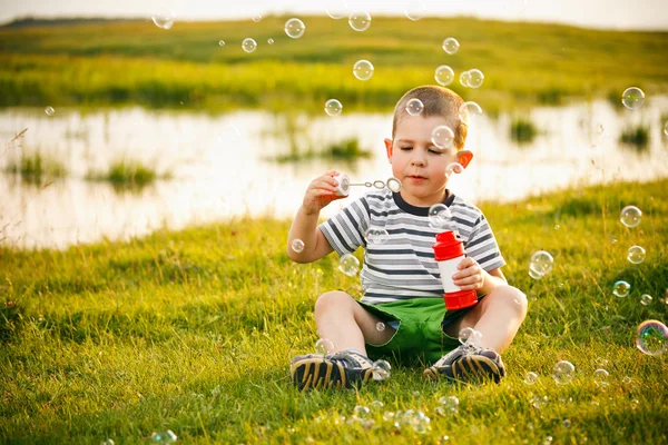 Pojken sitter på grönt gräs — Stockfoto