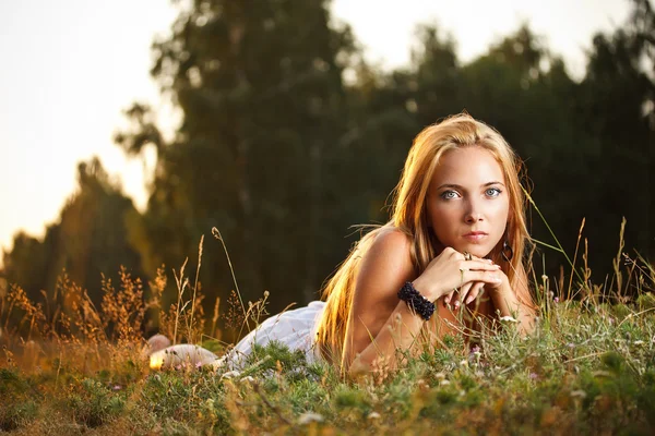 Mulher jovem que põe em uma grama — Fotografia de Stock