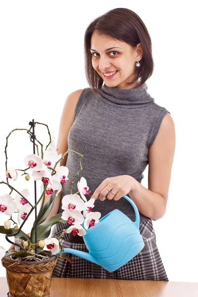Mladá žena zalévání orchidejí — Stock fotografie