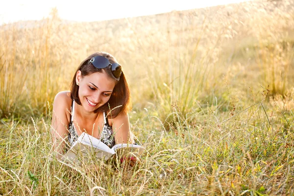 Mulher encontra-se na grama e lê livro — Fotografia de Stock