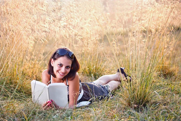 Женщина лежит на траве и читает книгу — стоковое фото