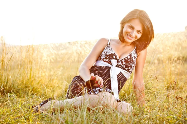 Genç bir kadın çimenlerde oturuyor. — Stok fotoğraf