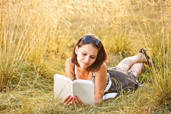 Frau liegt auf Gras und liest Buch — Stockfoto