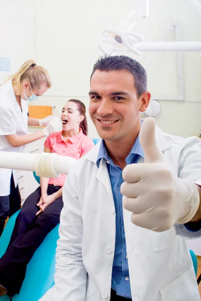 Dentista masculino amigable dando el pulgar hacia arriba signo — Foto de Stock