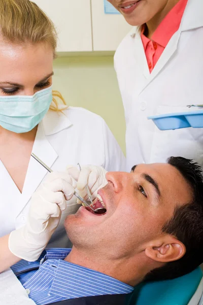 Dentista y asistente que trabaja en el paciente masculino — Foto de Stock