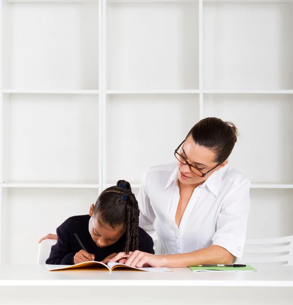 Заботливый учитель помогает школьнице с домашним заданием — стоковое фото