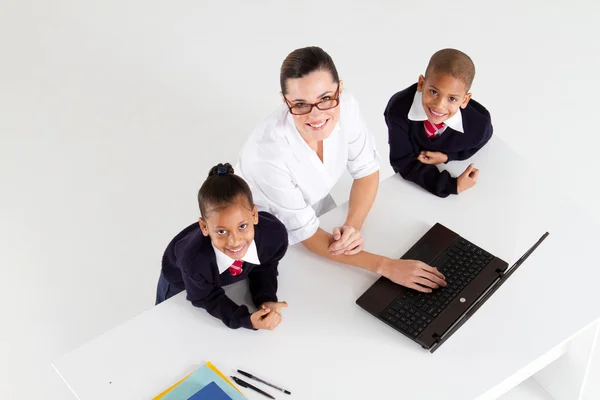 Elementary teacher and student in front of a laptop — Stok fotoğraf
