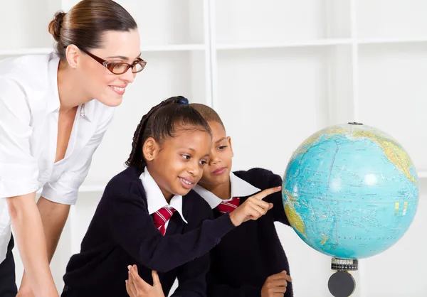 Elementära geografi lärare och studenter på globe — Stockfoto