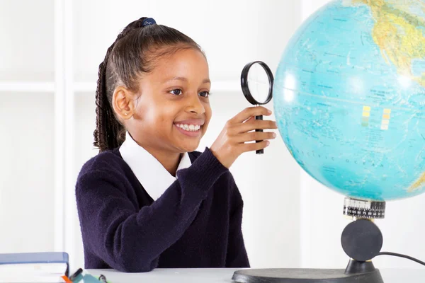Grundschülerin blickt auf Globus — Stockfoto