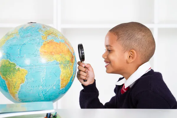 Estudante primário olhando para o globo — Fotografia de Stock