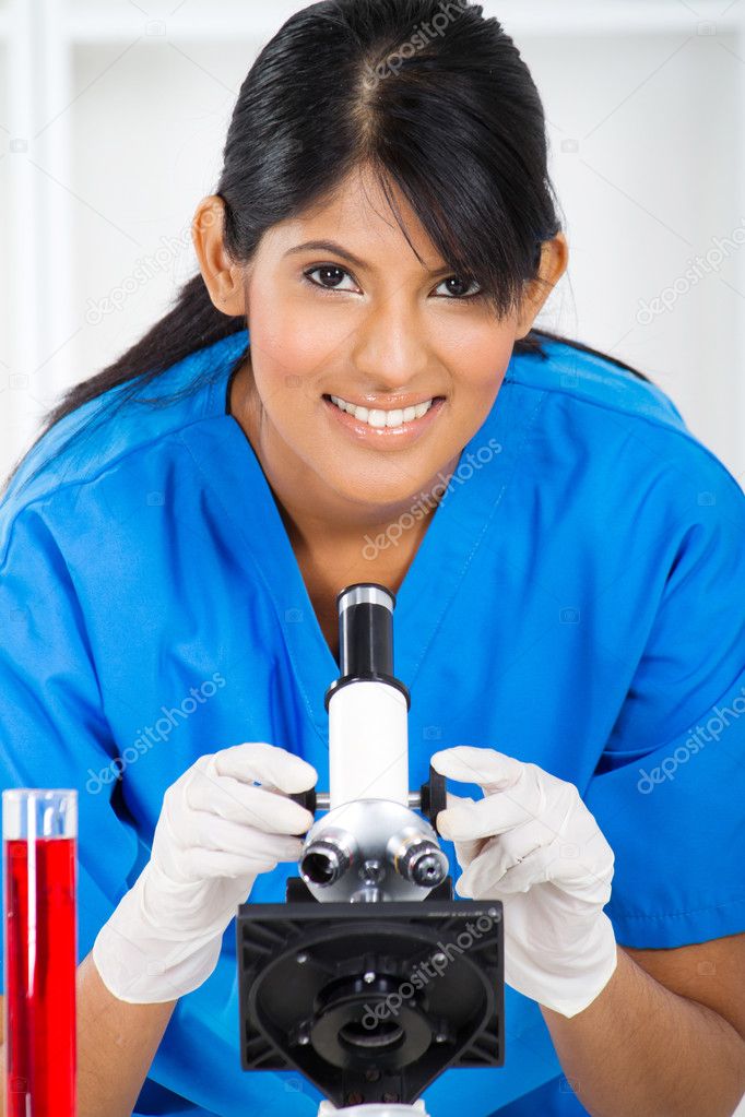 Young lab technician using microscope