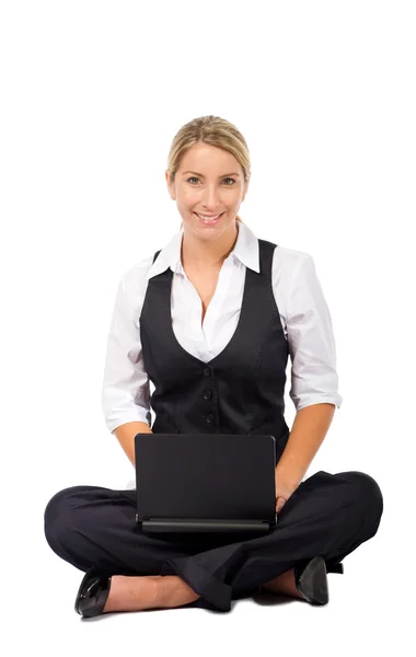 Katta oturan ve bir dizüstü bilgisayar üzerinde çalışan iş kadını — Stok fotoğraf
