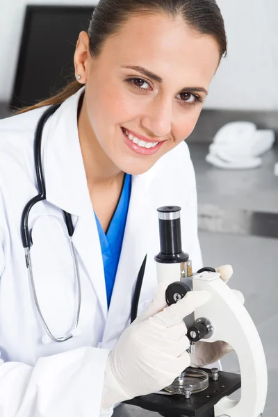 Giovane bella ricercatrice medica utilizzando il microscopio in laboratorio — Foto Stock