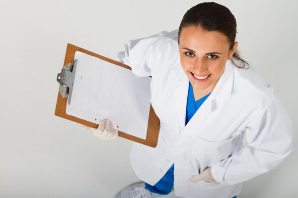 Young medical intern with clipboard looking up
