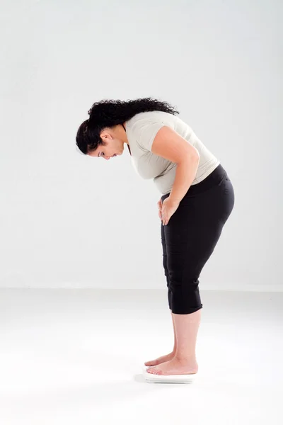 Женщина с избыточным весом стоит на весах — стоковое фото