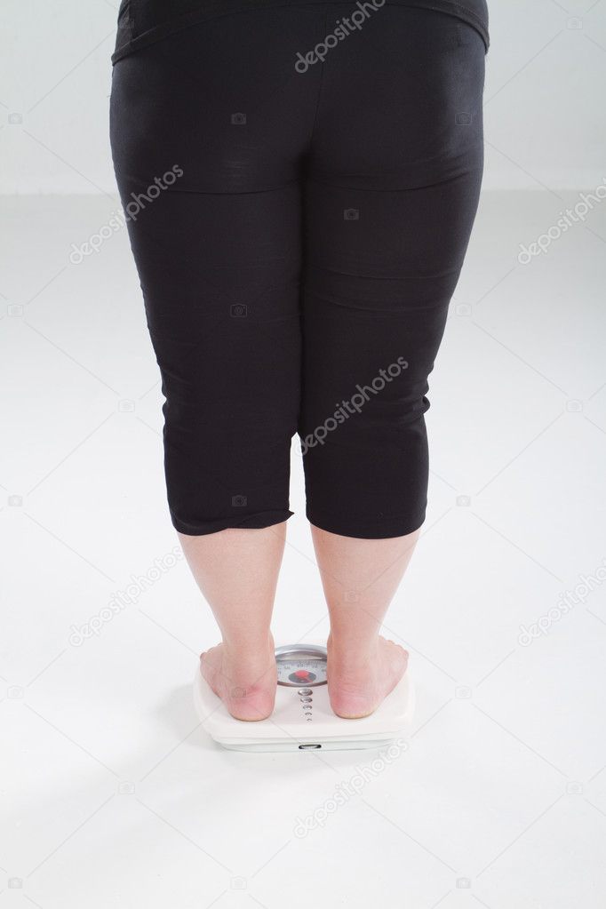 Overweight woman on scale weighting