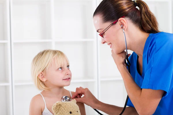 Jolie femme médecin examinant petite fille — Photo