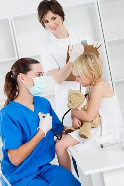 Медицинские работники играют с маленькой девочкой — стоковое фото