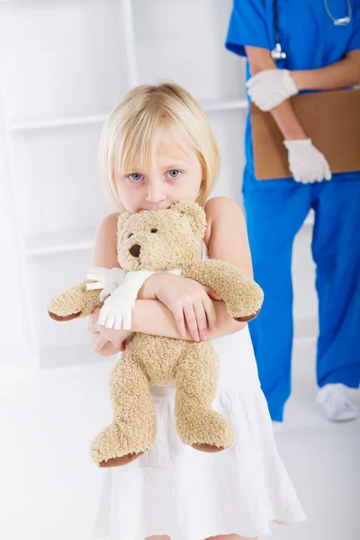 Menina segurando ursinho no consultório do médico — Fotografia de Stock