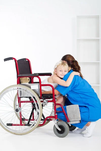 Niña pequeña paciente en silla de ruedas abrazo médico —  Fotos de Stock