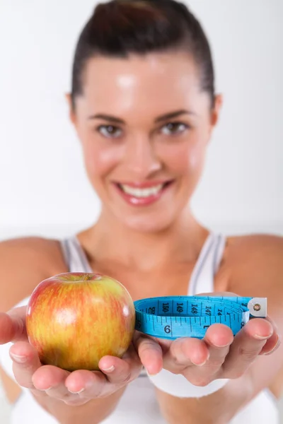 Фитнес-женщина с яблочной и измерительной лентой — стоковое фото